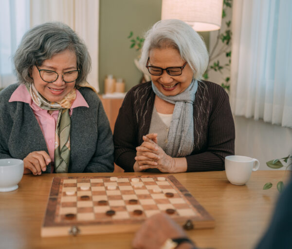 Happy senior friends play chess at a senior center.